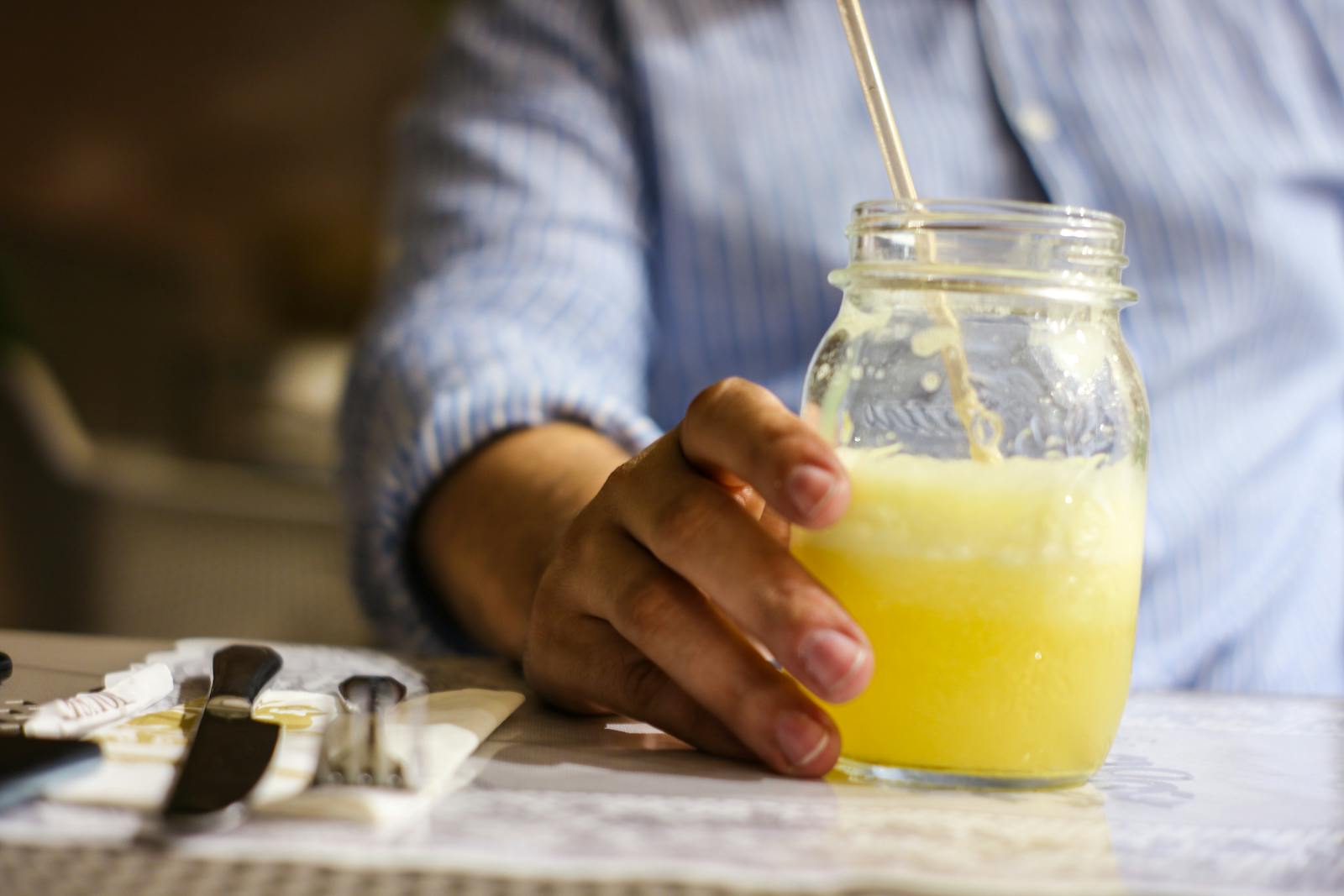 Hand holding mason jar with yellow juice