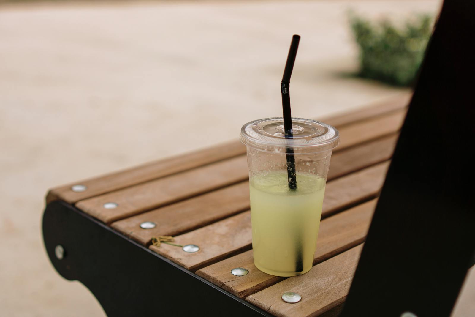 Plastic cup of lemonade on wooden bench