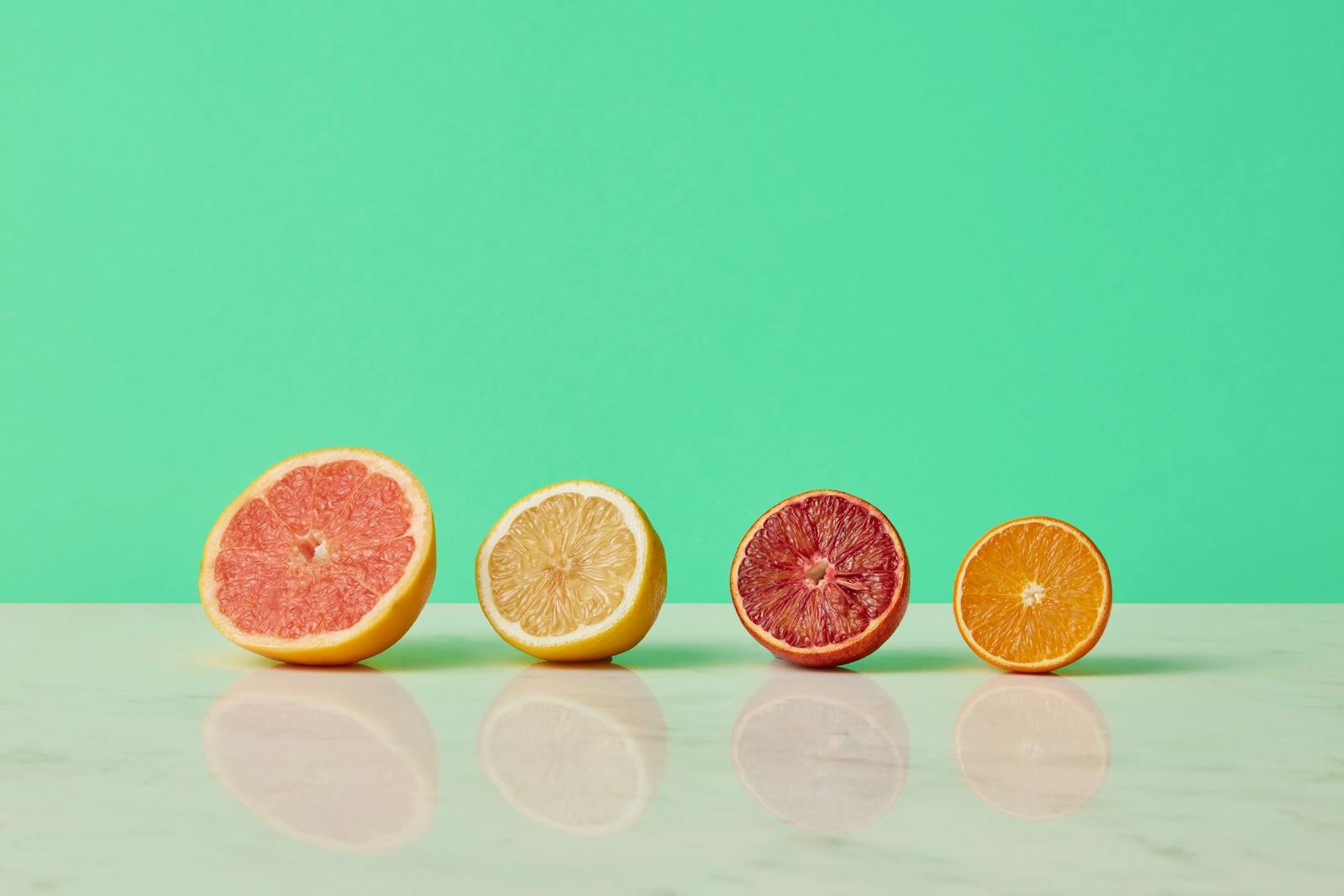 Citrus fruit halves on green background