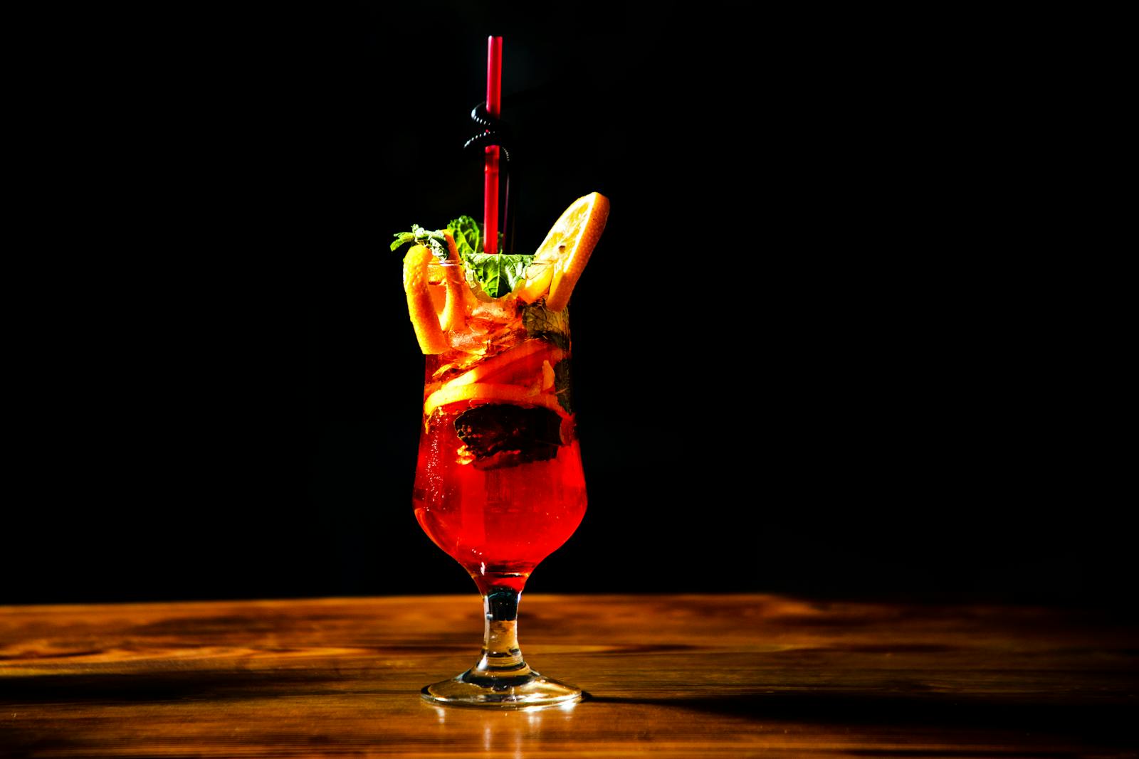 Red cocktail with orange garnish on table