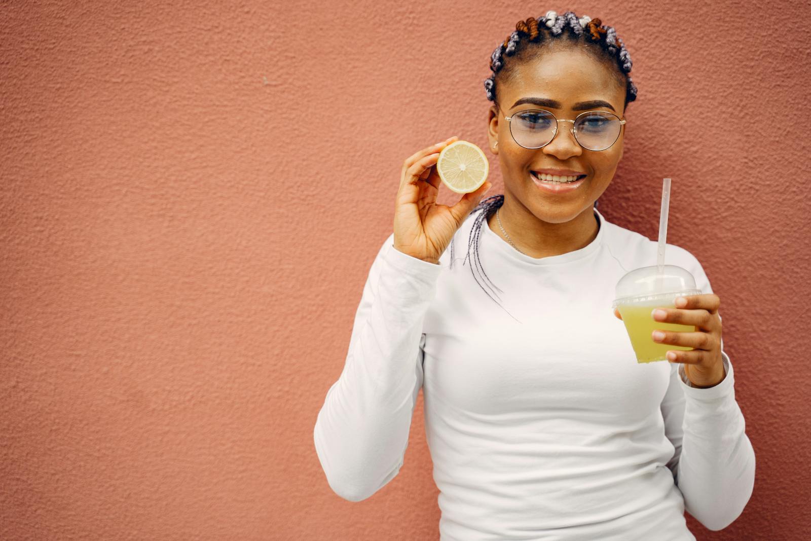 Smiling woman holding lemon and juice