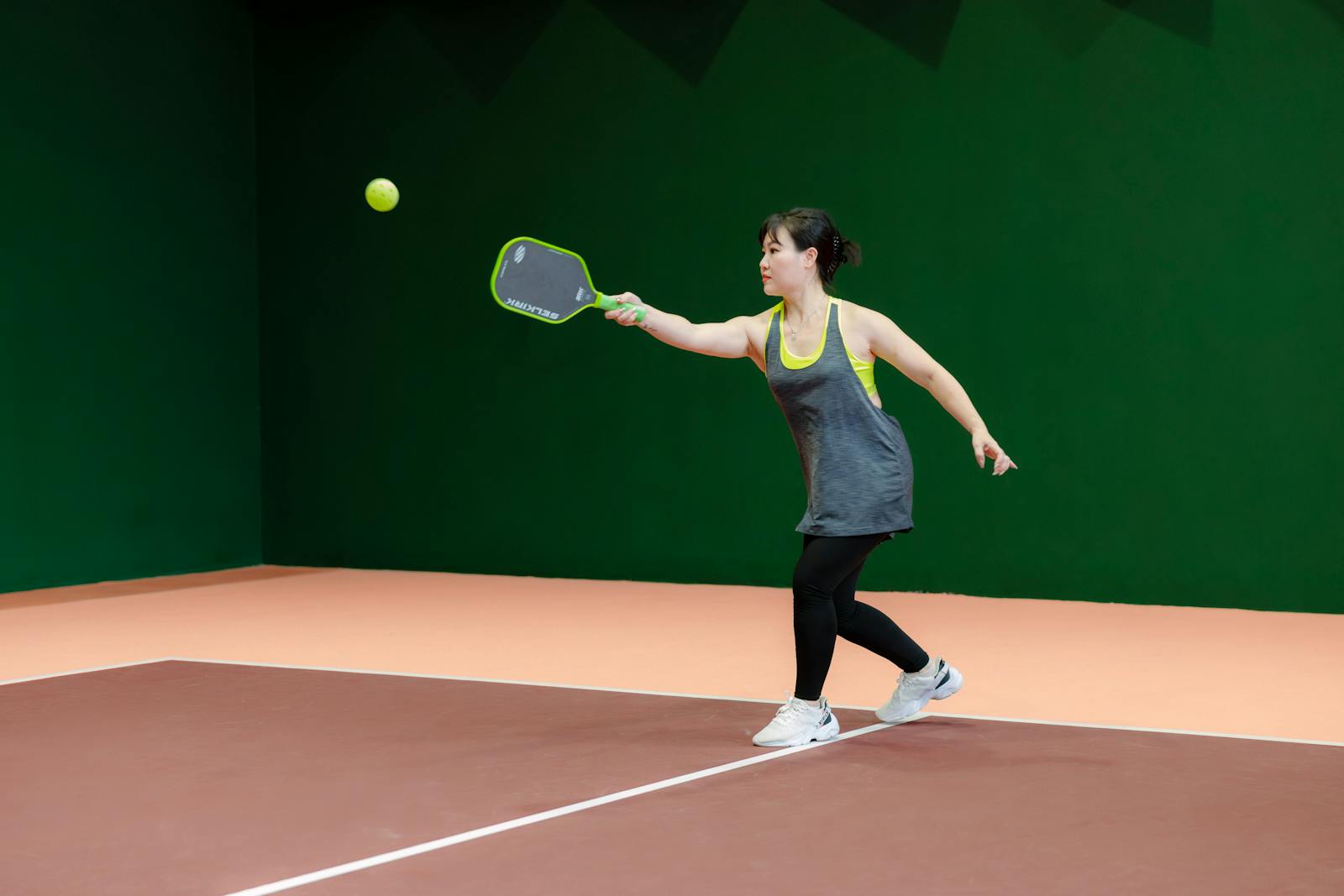Woman playing pickleball indoors with paddle