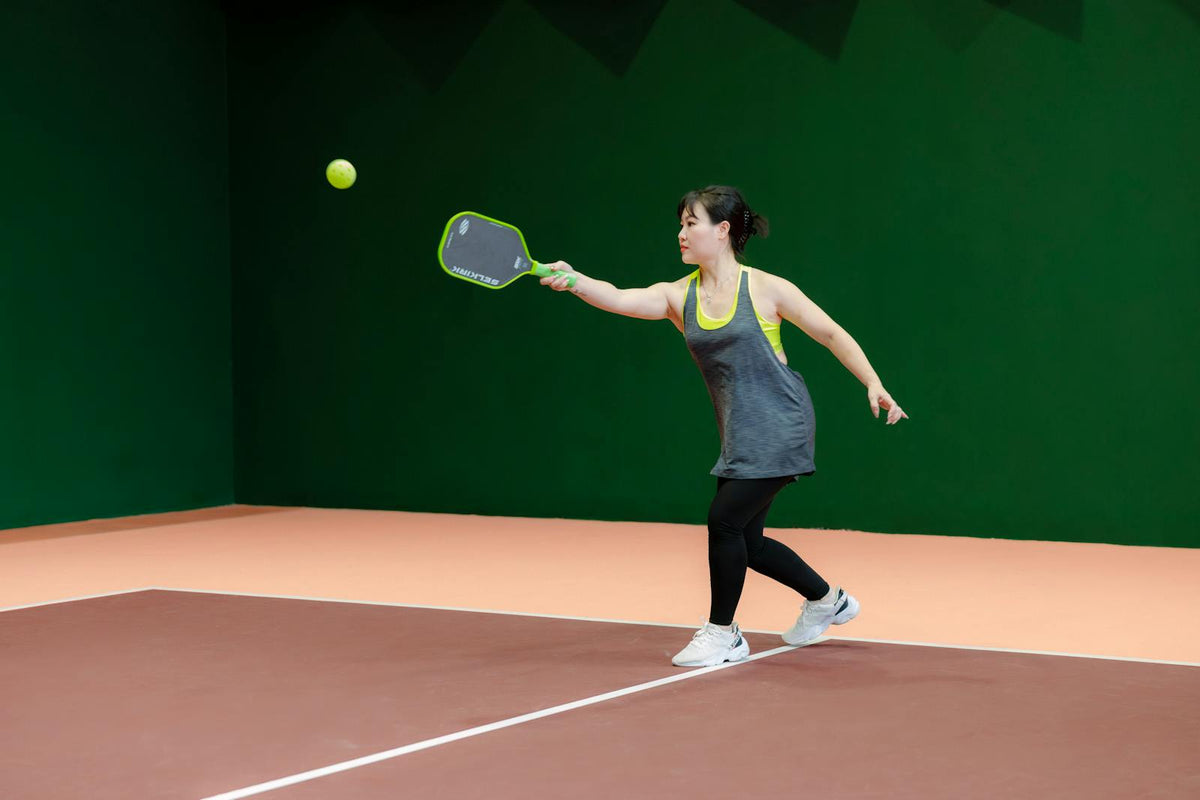 Woman playing pickleball indoors with paddle