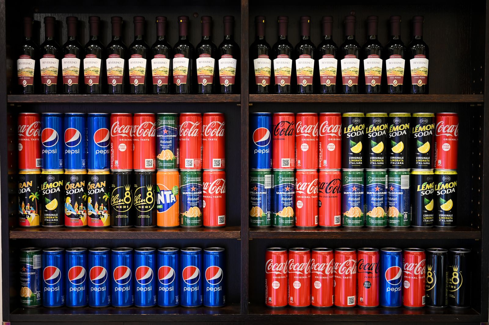 Shelf with assorted soda cans and wine bottles