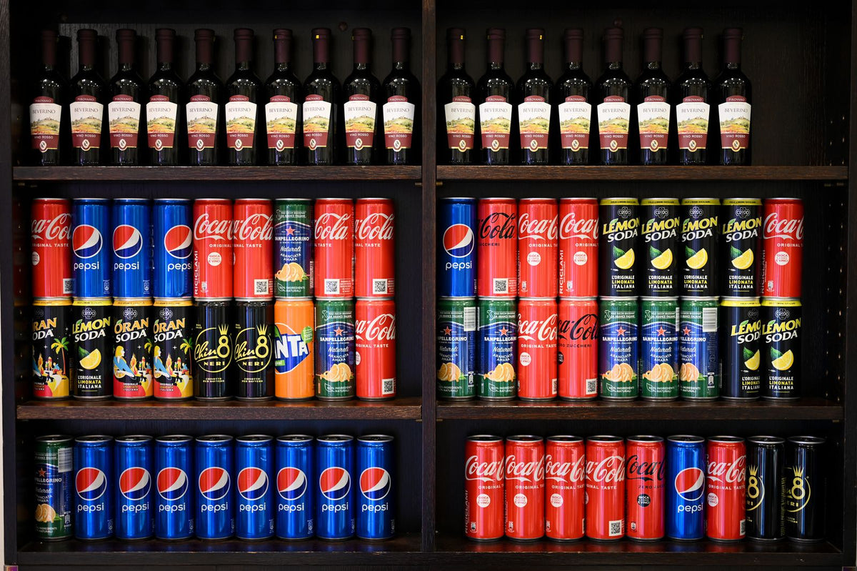 Shelf with assorted soda cans and wine bottles