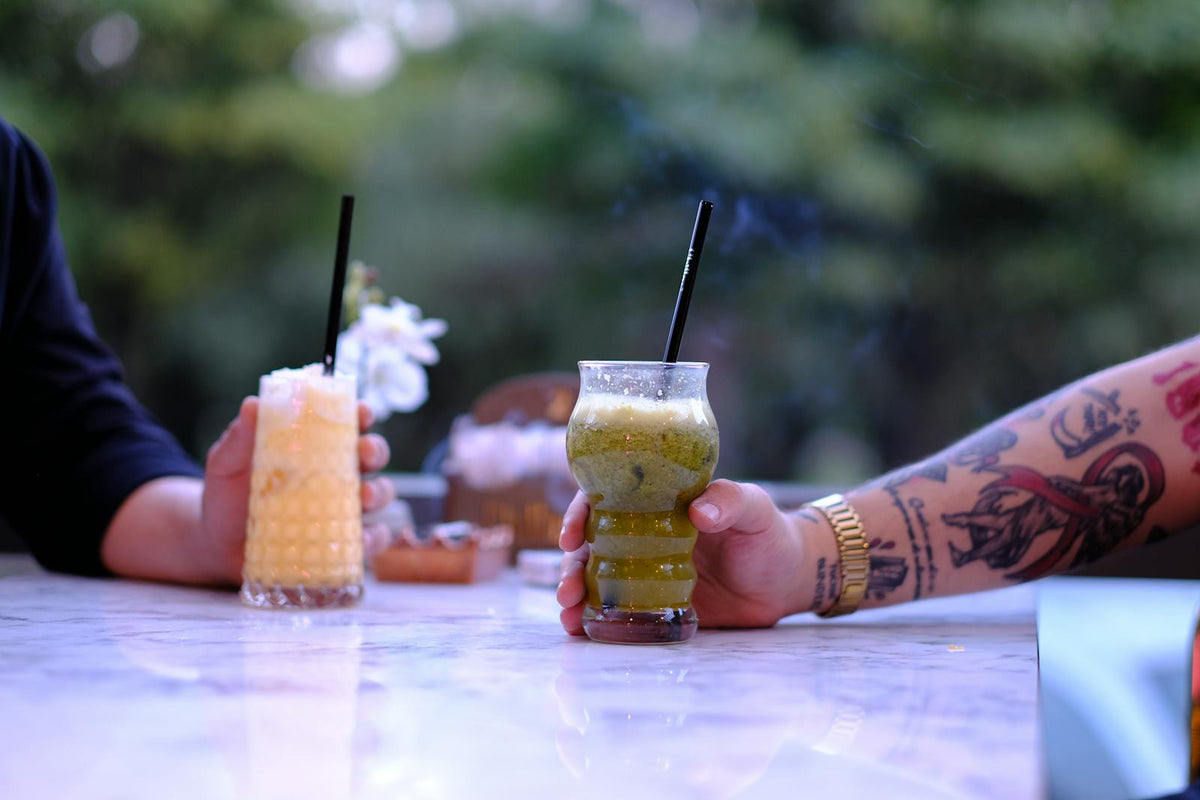 Tattooed hand holding a green smoothie
