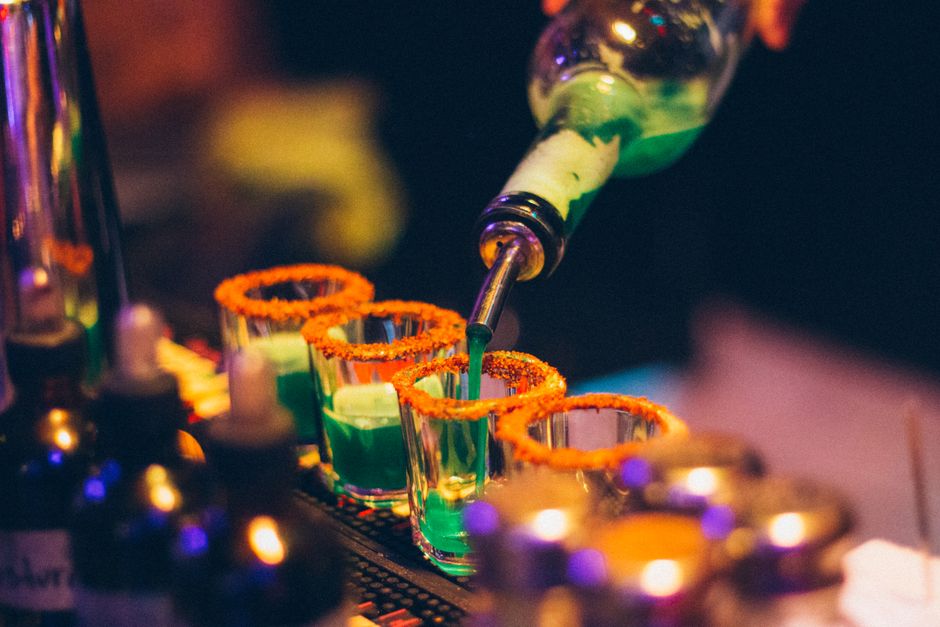 Bartender pouring green shots with orange rims