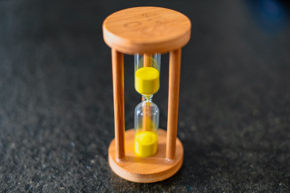 Hourglass with yellow sand on dark surface