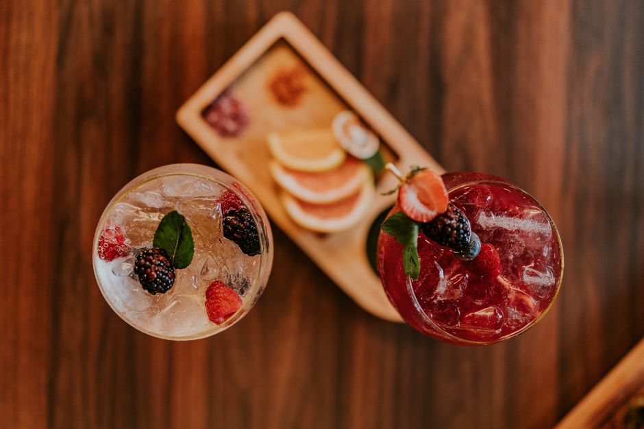 Two berry cocktails with ice and fruit garnish