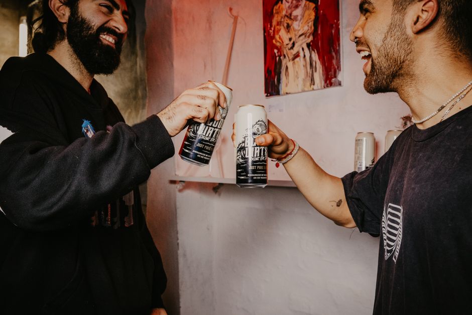 Two men laughing and clinking beer cans