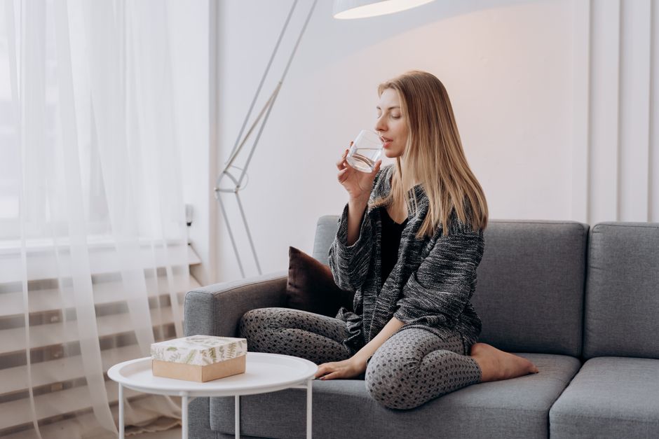 Woman sitting on sofa drinking water