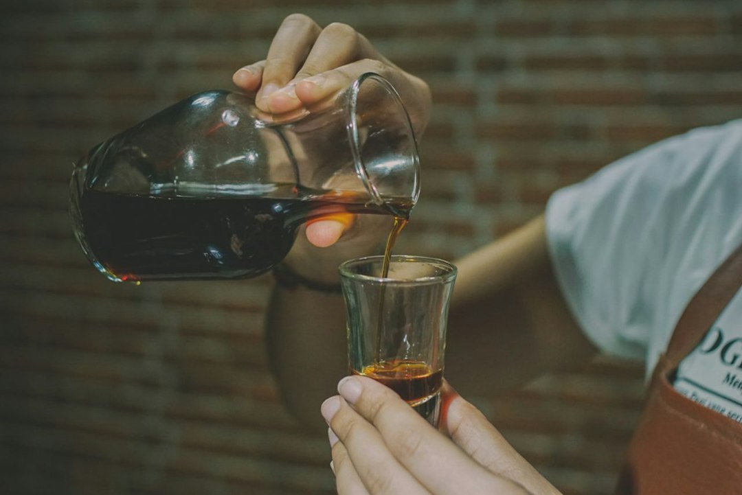 Person pouring coffee from carafe into glass