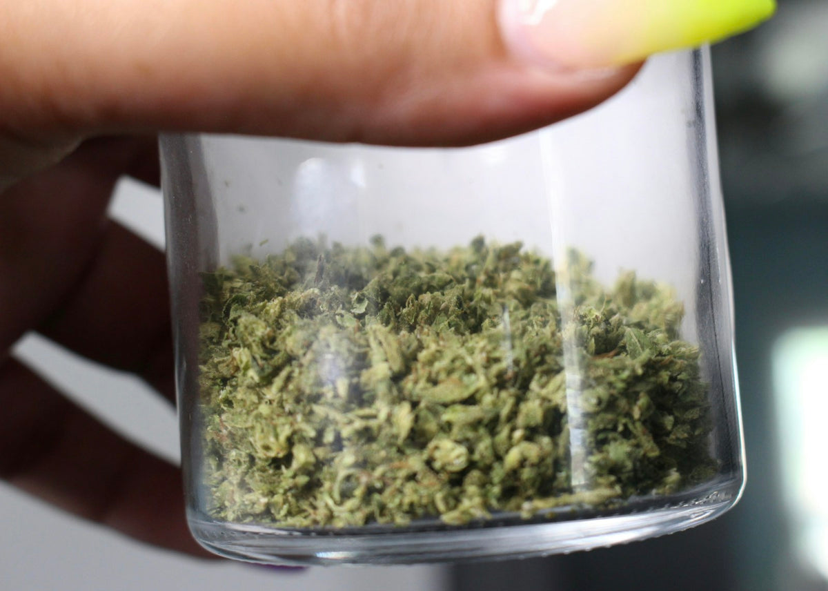 Hand holding jar of dried herbal leaves
