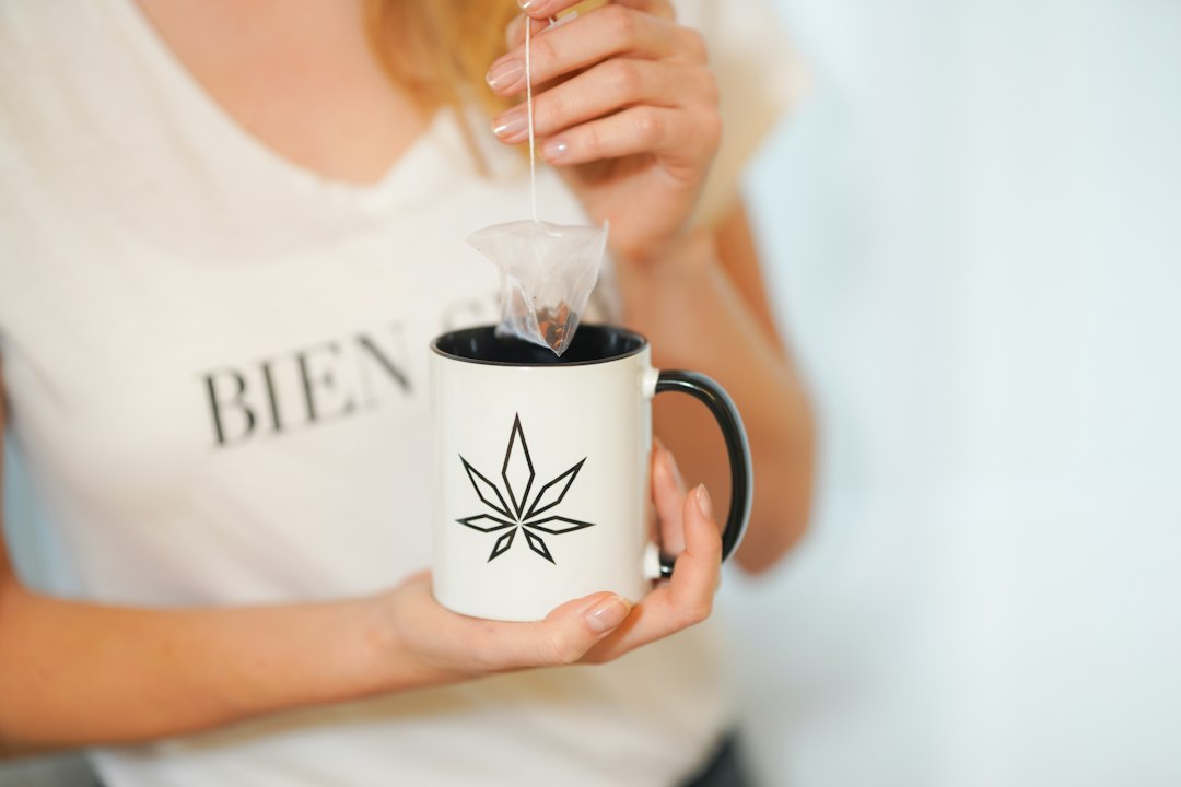 Hand holding mug with cannabis leaf design