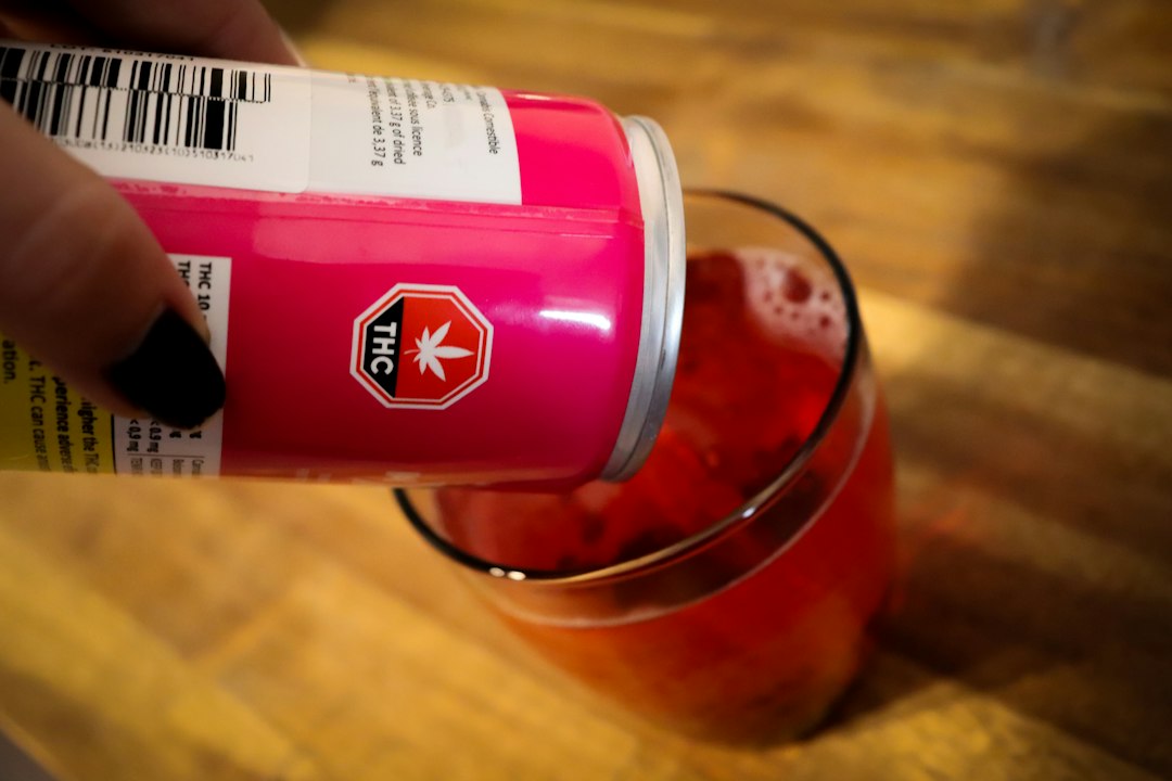 Hand pours pink THC can into glass