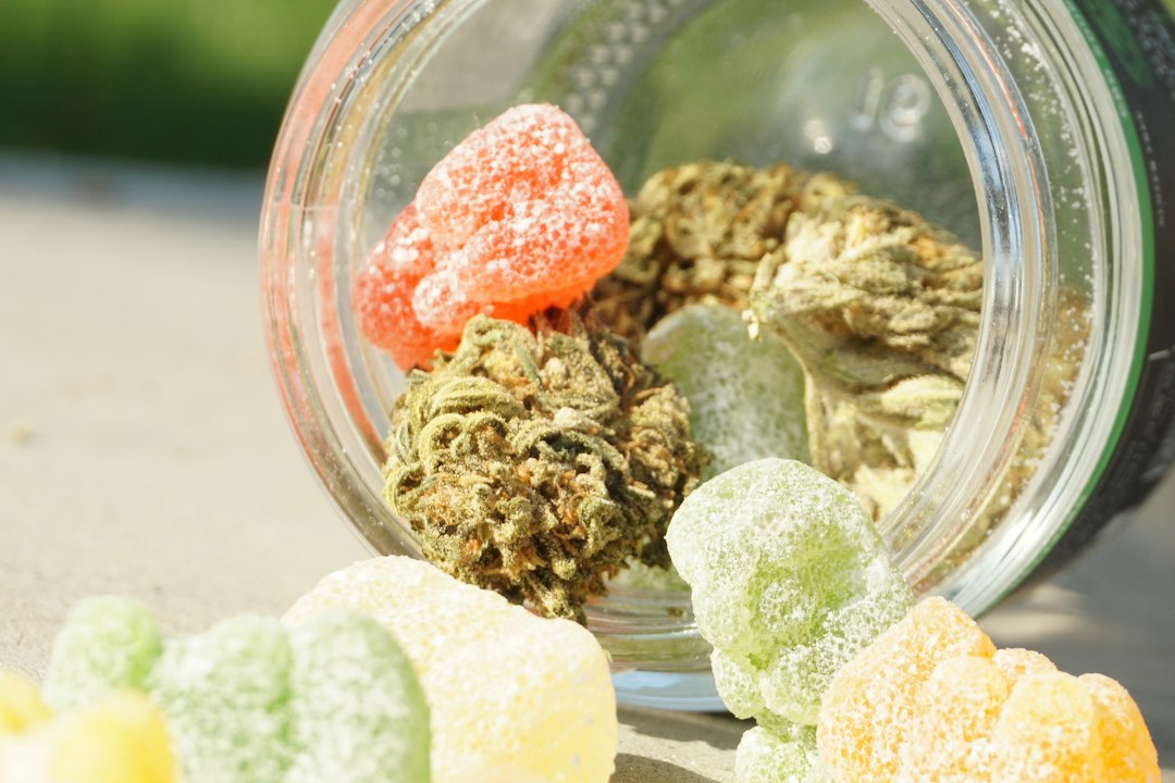 Jar with cannabis buds and colorful gummies