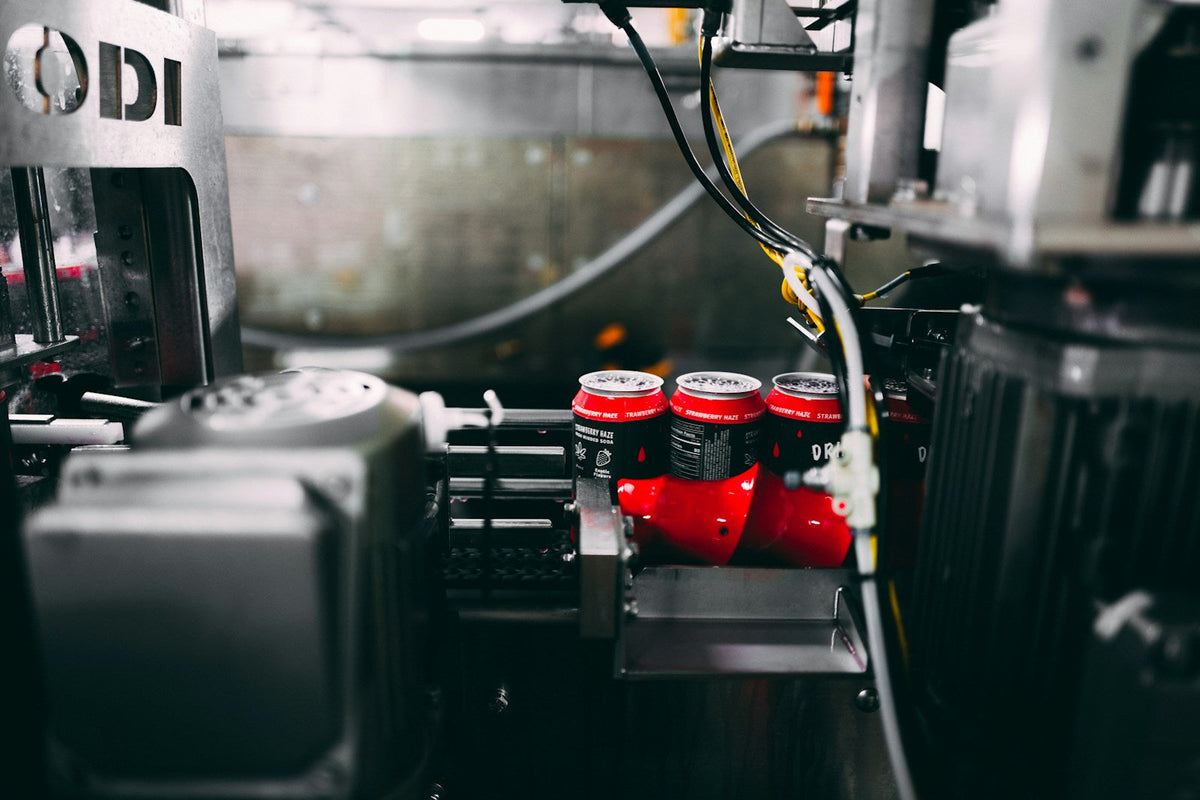 Canning machine processing red beverage cans