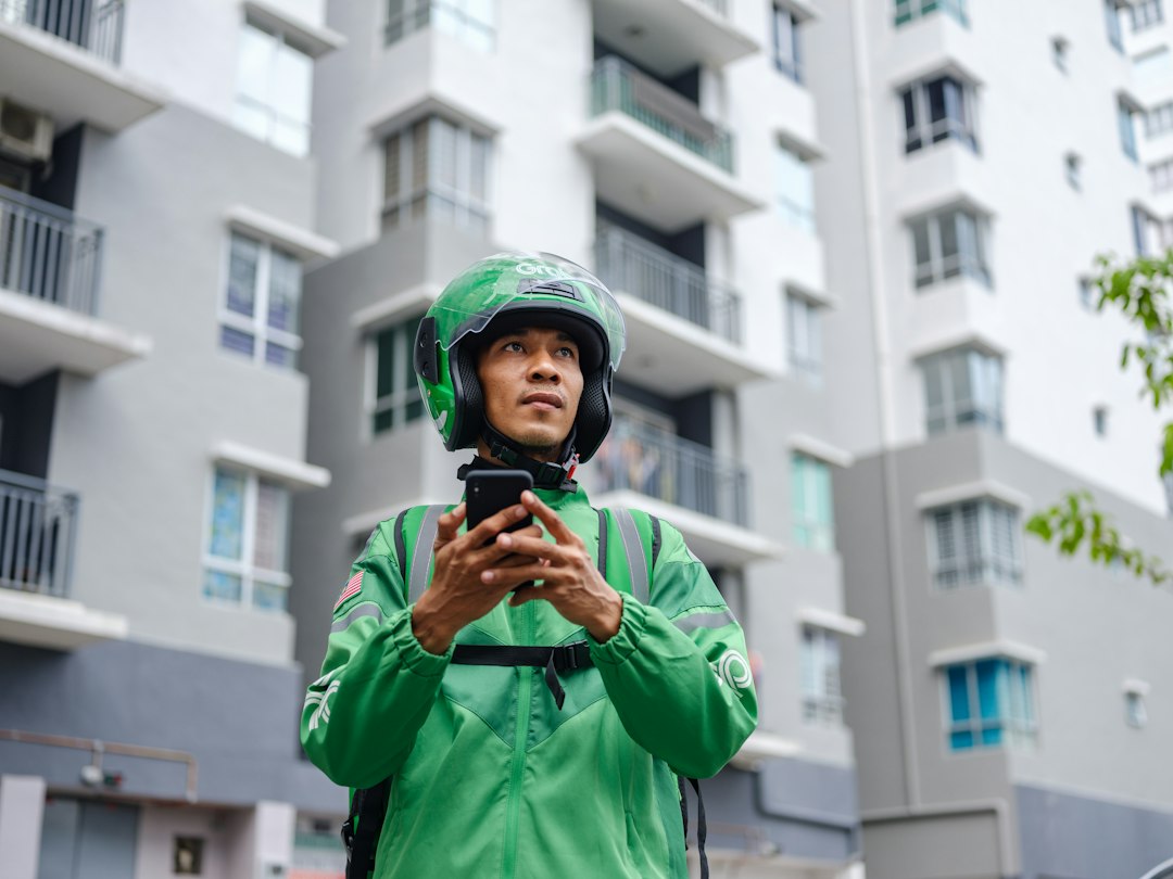 Delivery driver in green jacket with phone